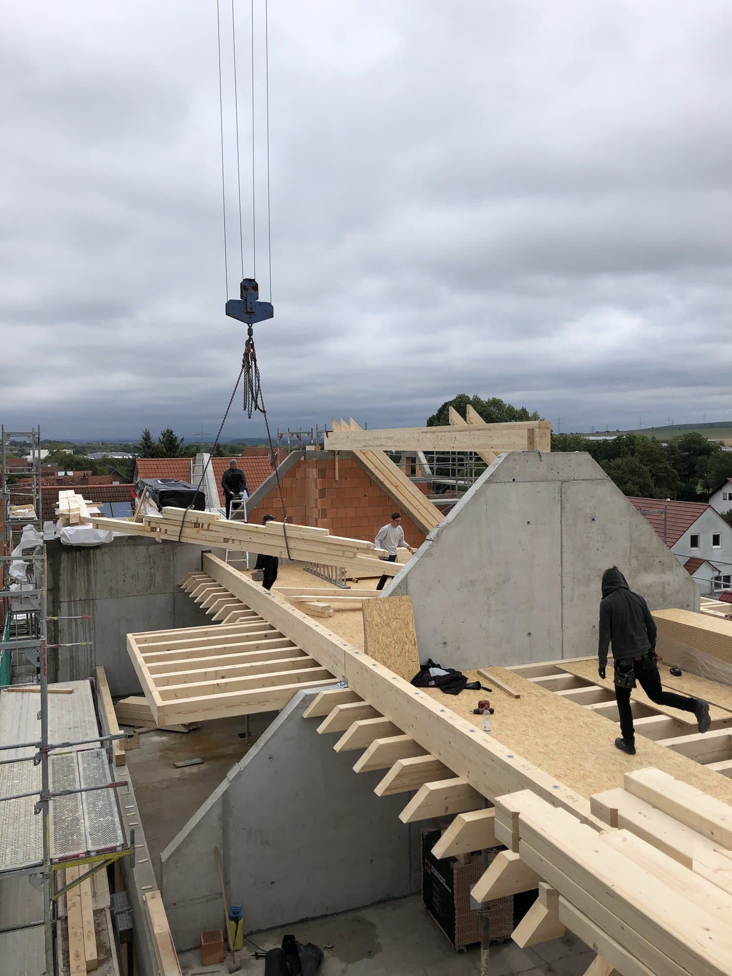 Zimmerer von Heckler Holzbau steuert beim Einheben der Holzbalken den Kran